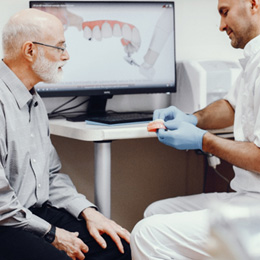 A dentist showing dentures to an older man