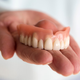 A closeup of a hand holding a removable denture