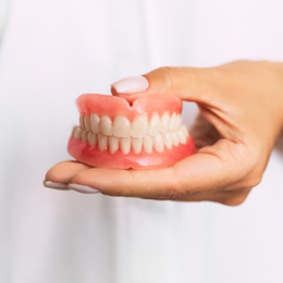 A dentist holding dentures in front of their chest