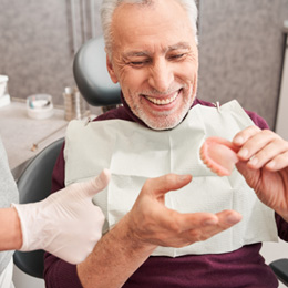 A dentist showing dentures to her older patient
