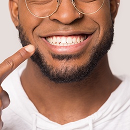 man smiling and pointing to teeth 