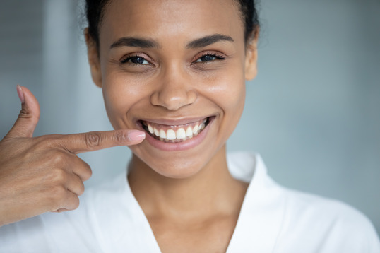 patient smiling while pointing to teeth  