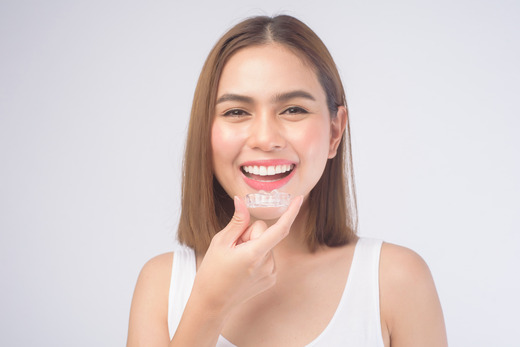 woman smiling while holding clear aligner 